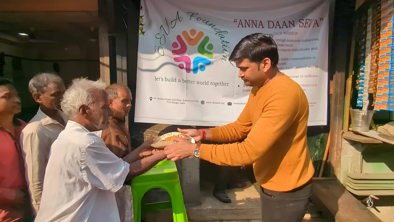 A SEVA volunteer serving a meal to an elderly man at Anna Daan Seva
